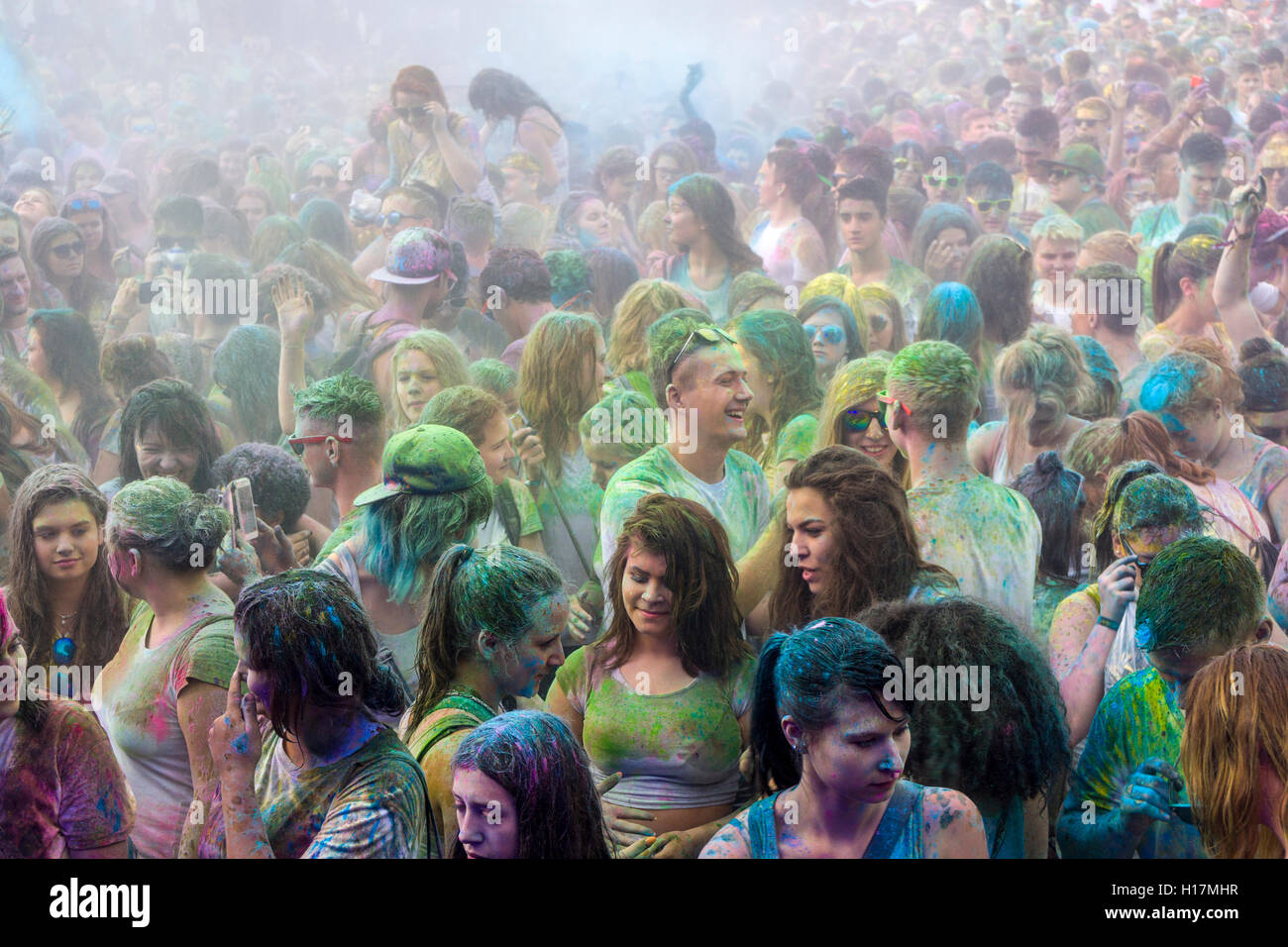 Miles de jóvenes hombres y mujeres apenas son visibles porque de color en polvo en el aire en el colorido festival de Holi, Dresde Foto de stock