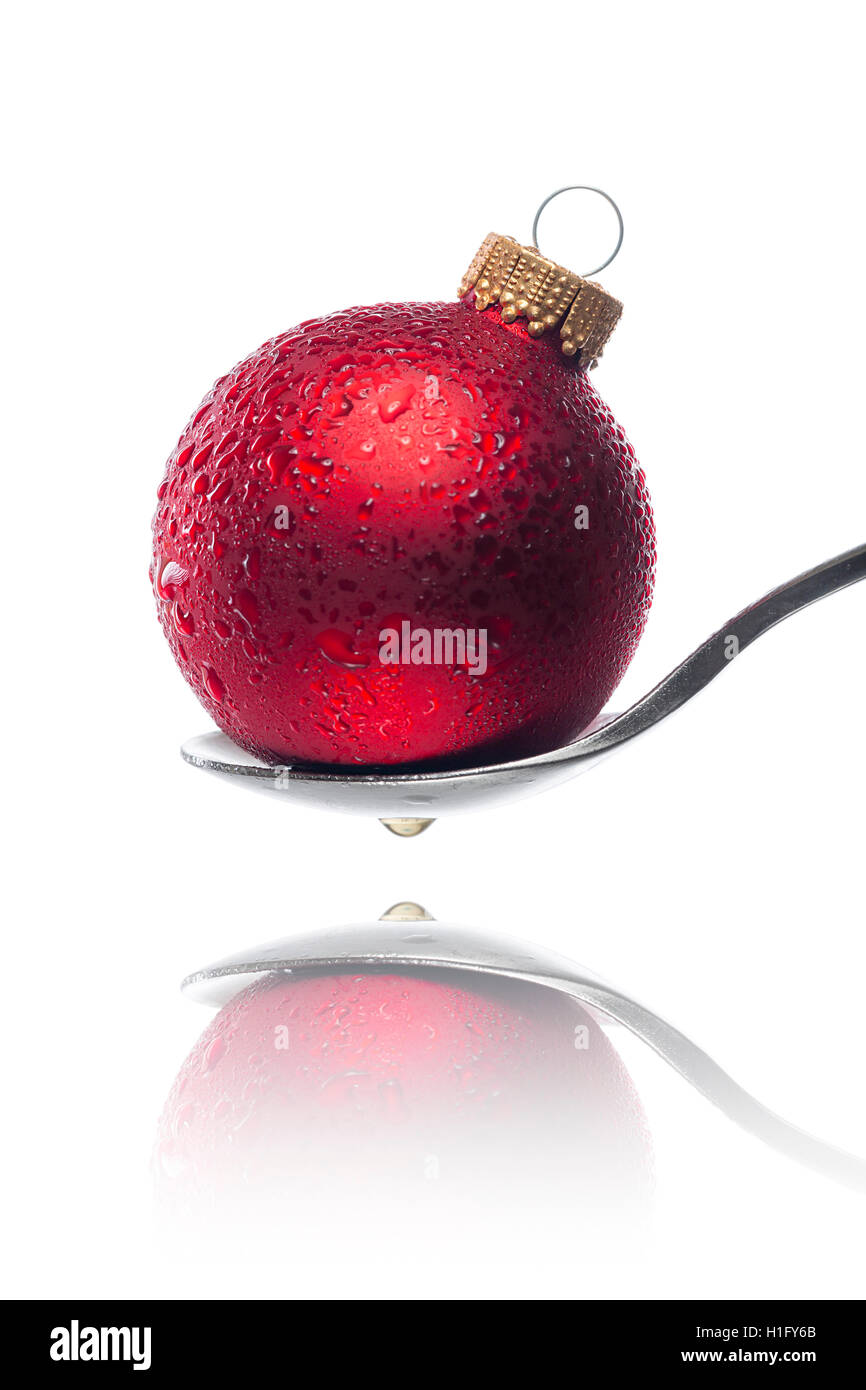 Bola de Navidad roja con gotas de agua sobre una cuchara Foto de stock
