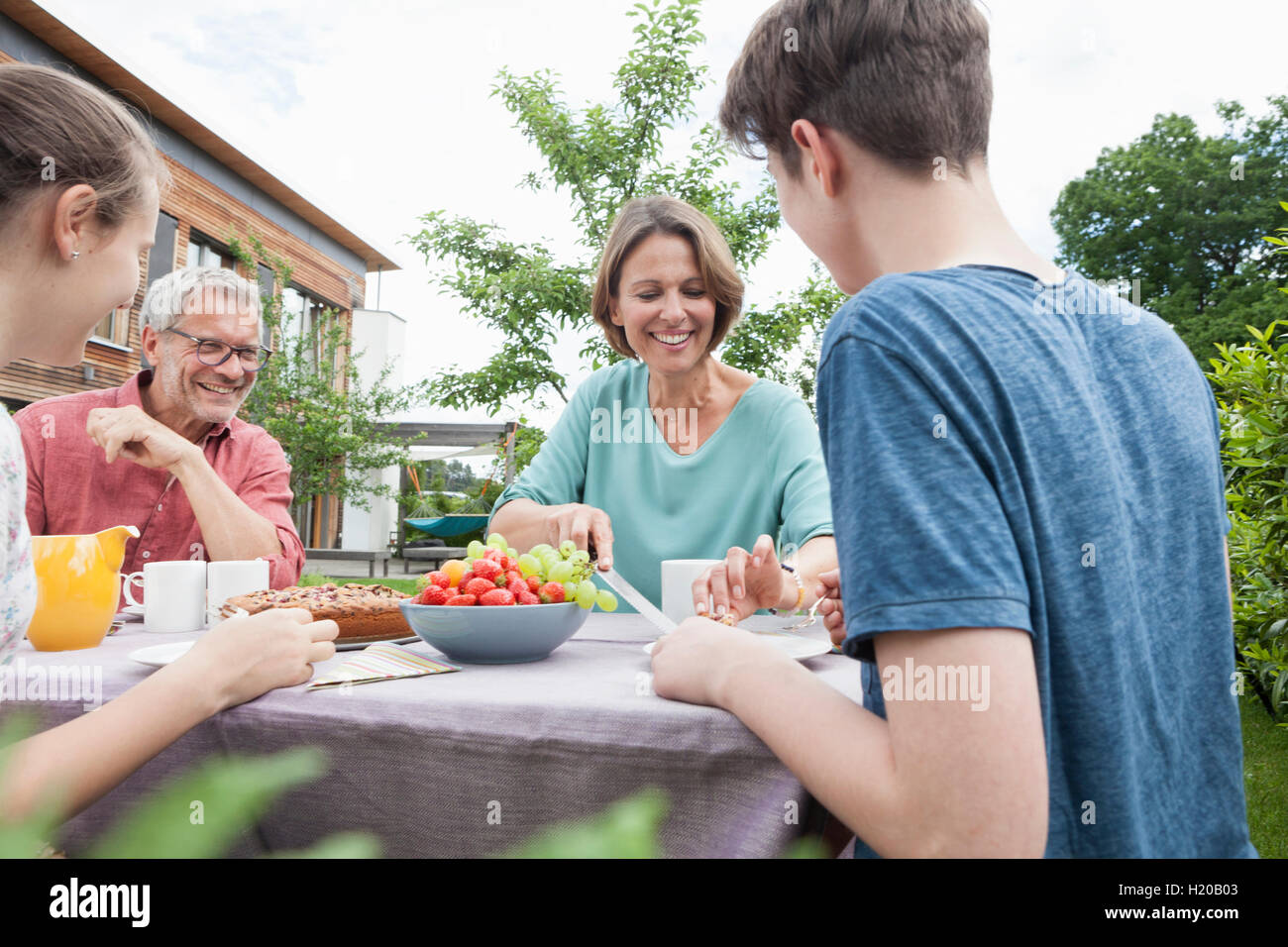 Familia Feliz en el jardín tras almorzar Foto de stock