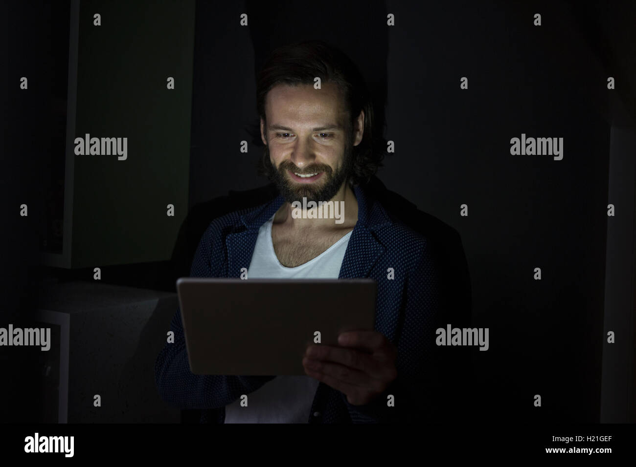 Hombre utilizando tablet digital en la oscuridad Foto de stock