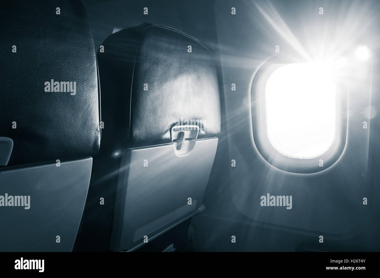 Avión de pasajeros fragmento interior. Cabina principal sillas con mesa plegable y resplandeciente de ojo de buey con luz natural los brillos de la lente. B Foto de stock