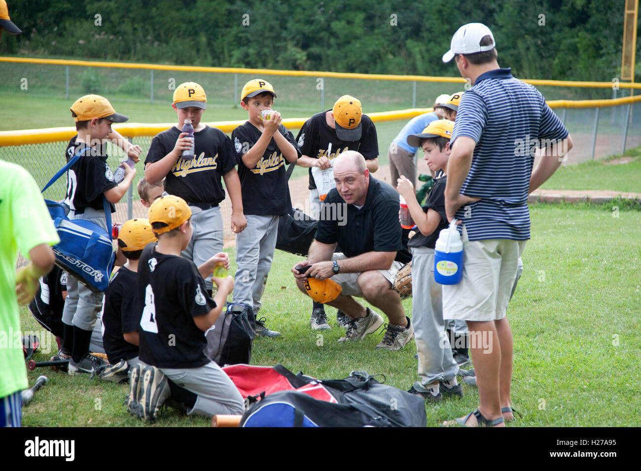 El entrenador del equipo de béisbol de los muchachos sedientos instruyendo a los 10 años de edad y 45 St Paul MN Minnesota EE.UU. Foto de stock
