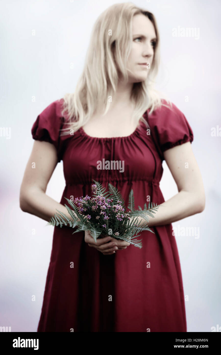 Una mujer en un vestido rojo con un ramo de flores Foto de stock