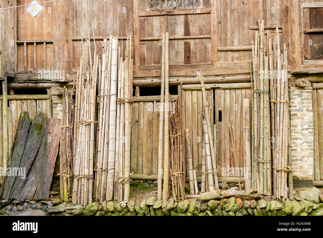 Las paredes de madera de la casa de pueblo con palos de bambú atadas contra  la pared inclinada en China Fotografía de stock - Alamy