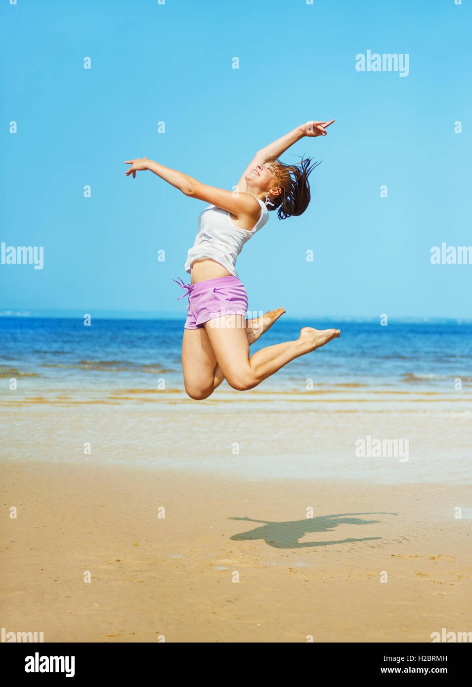 Hermosa joven enérgico salto en la playa Foto de stock
