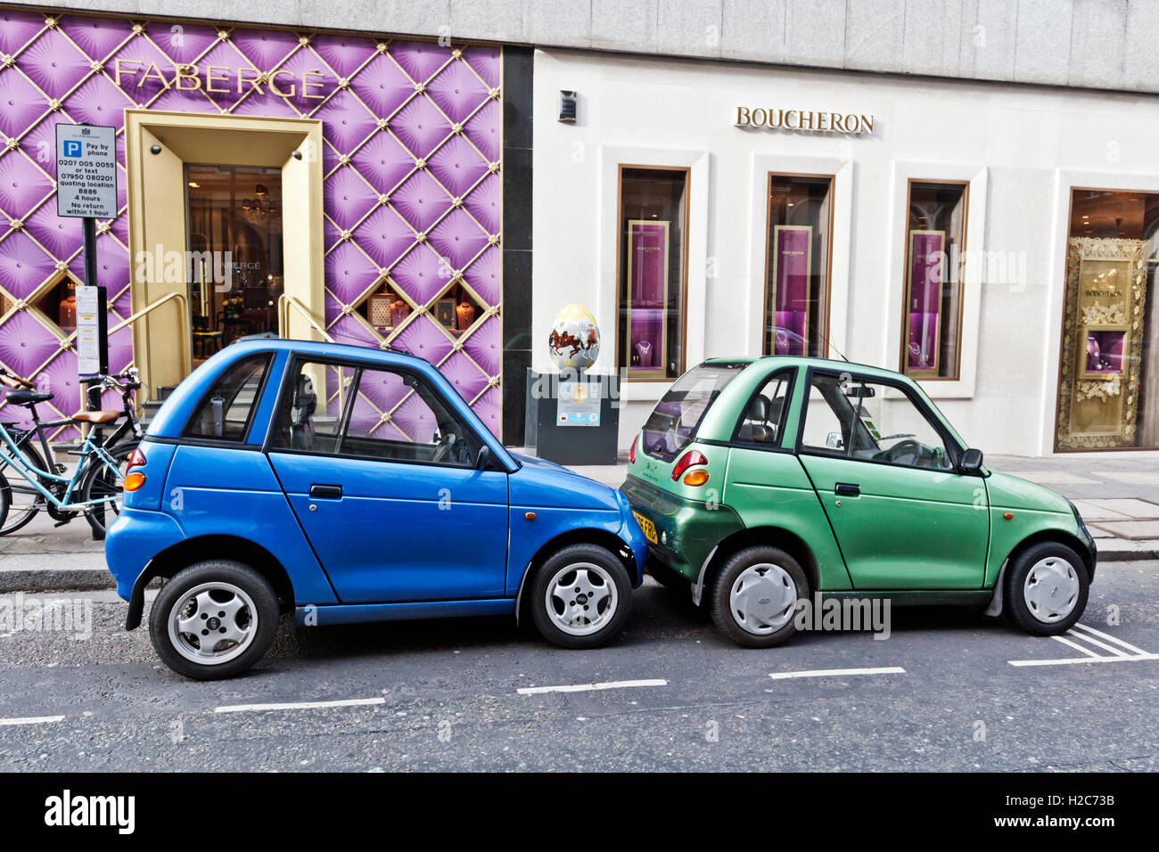 Dos cute G-Wiz coches eléctricos compartir espacio de aparcamiento, Mayfair, Londres W1, Inglaterra, Reino Unido. Foto de stock