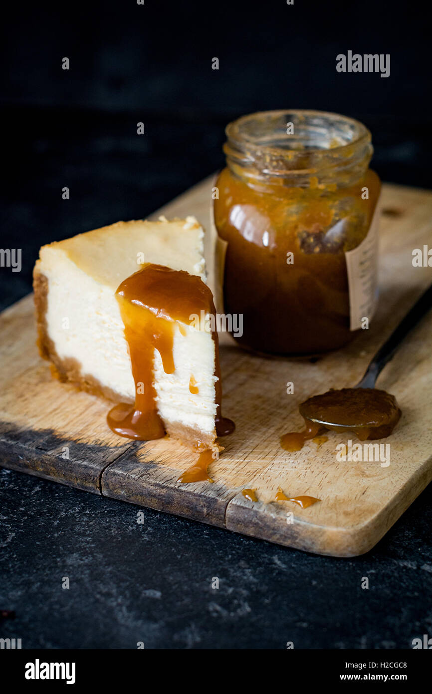 Cheesecake con salsa de caramelo sobre una tabla de cortar de madera. Cerca, el enfoque selectivo Foto de stock