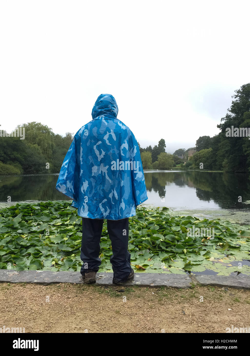 Mujer riendo vistiendo un poncho de plástico durante una ducha de lluvia  Fotografía de stock - Alamy