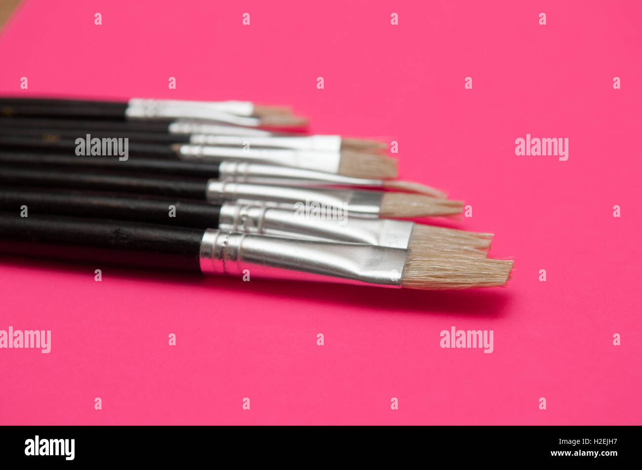 Artistas pinceles y plumas aparece sobre fondo de color rosa aislado Foto de stock