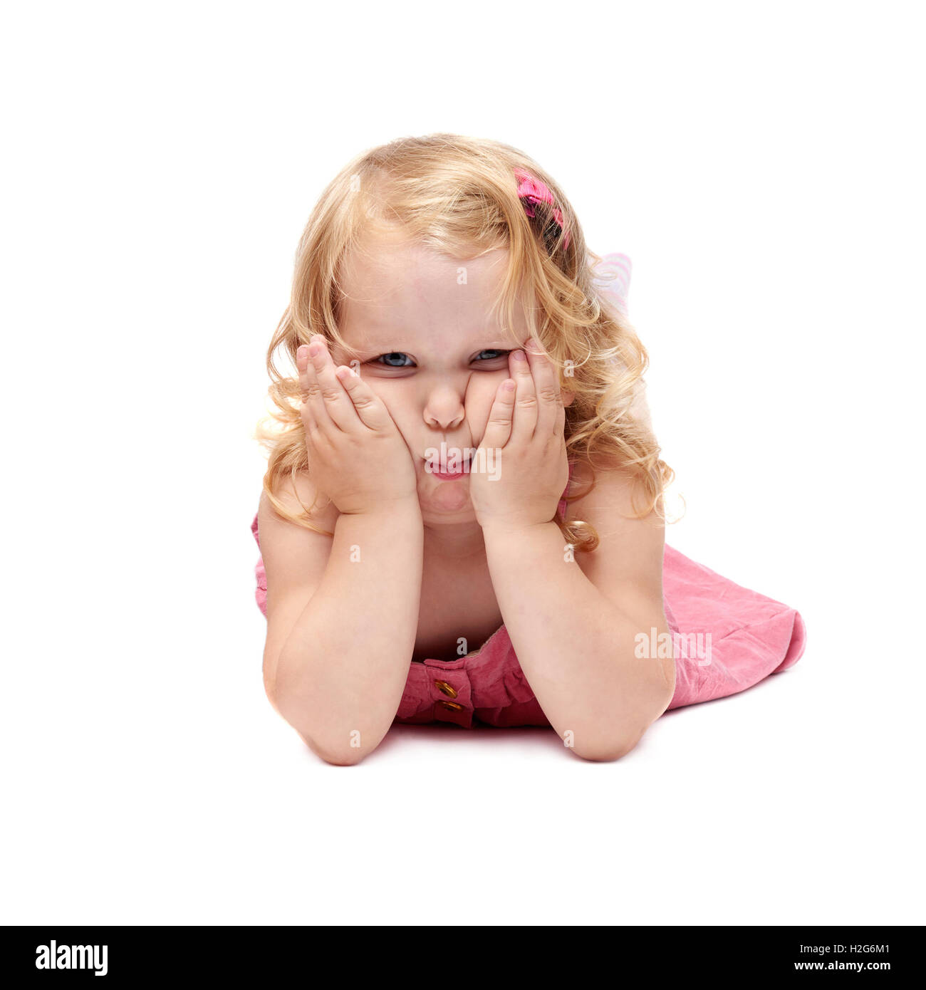 Pequeña niña recostada sobre fondo blanco aislado Foto de stock