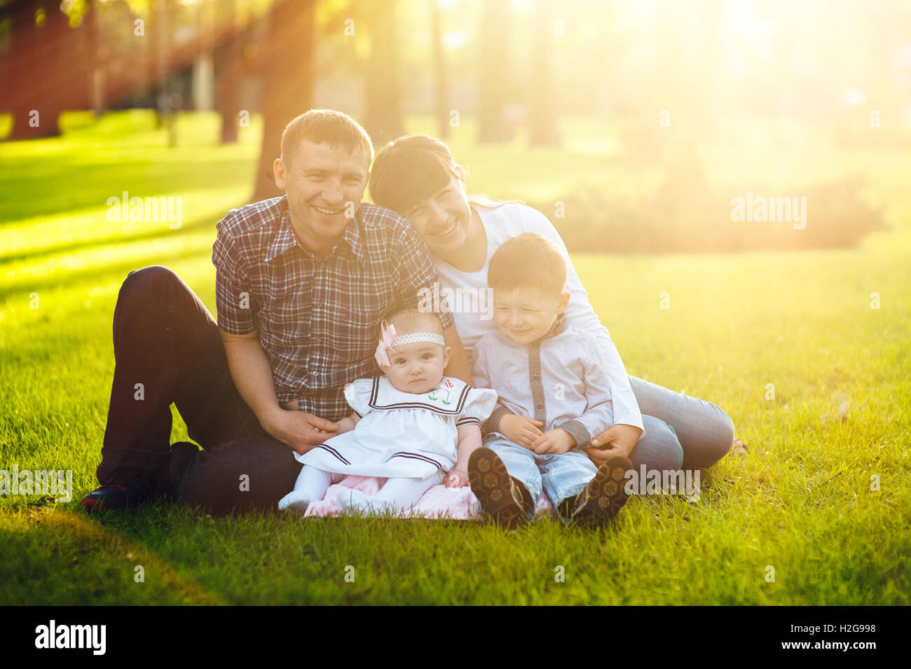 Una familia joven con dos niños caminando en un parque de verano Foto de stock