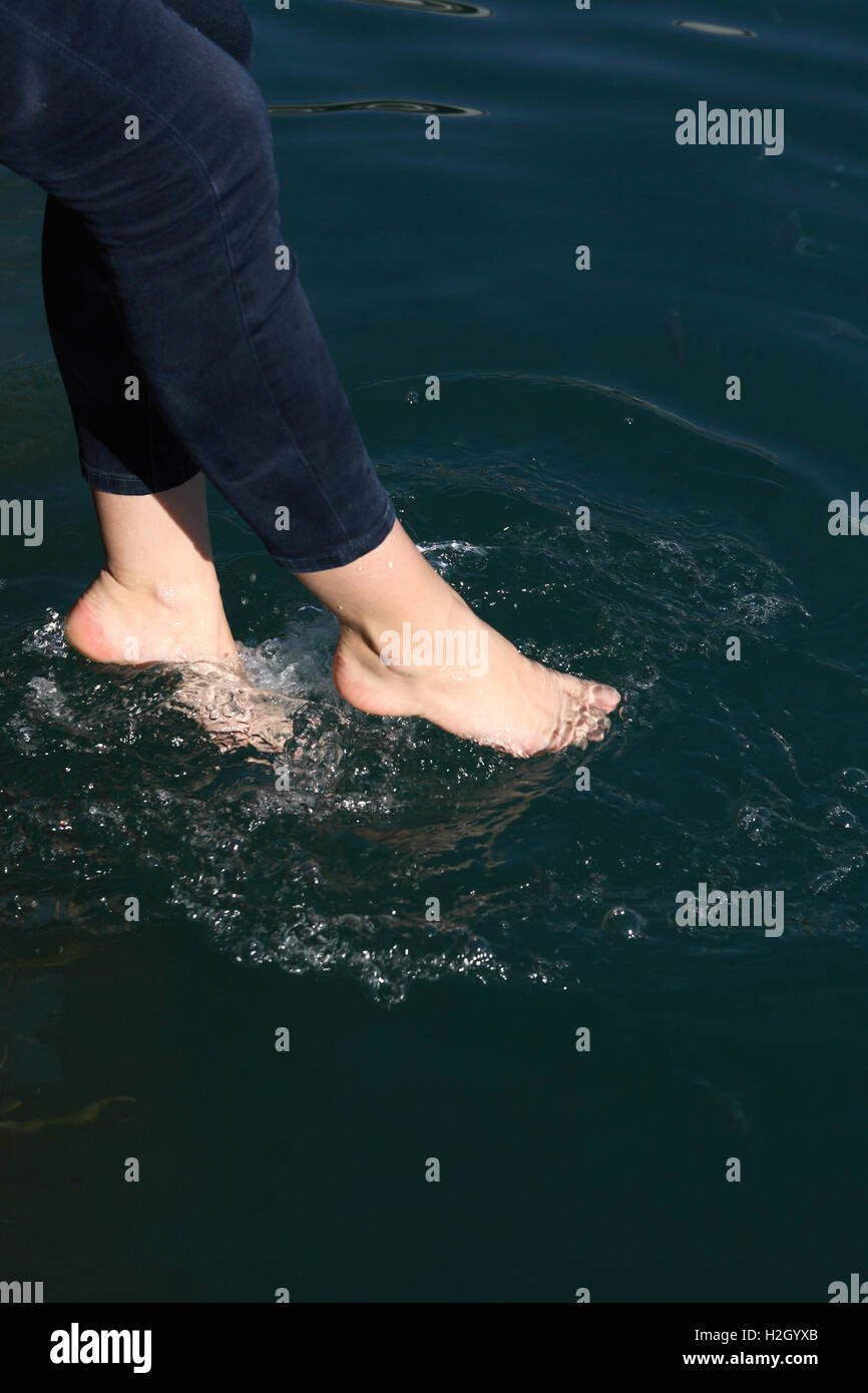 Primer plano de los pies femeninos las salpicaduras de agua de mar Foto de stock