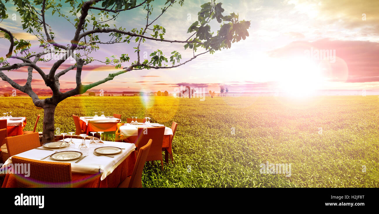 Idílico restaurante al aire libre en los campos verdes y el atardecer Foto de stock