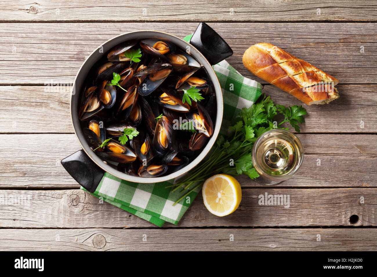 Mejillones en olla de cobre y vino blanco sobre la mesa de madera. Vista superior Foto de stock