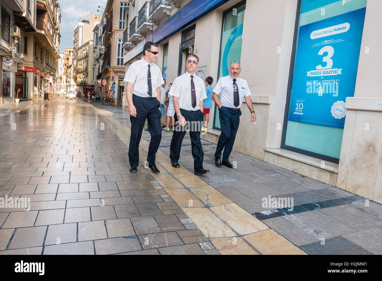3 empresarios españoles caminando por una calle en Málaga, España usando  los mismos trajes, camisas blancas, corbatas negras, zapatos y ganchos de  amarre Fotografía de stock - Alamy