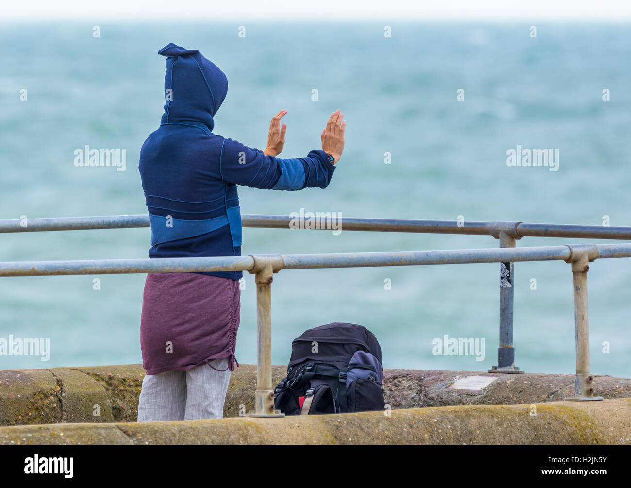 Mujer practicando yoga junto al mar. Foto de stock