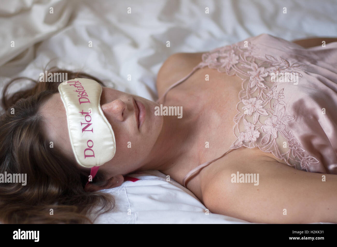 Joven mujer caucásica relajante con "No molestar" máscara de ojo Foto de stock