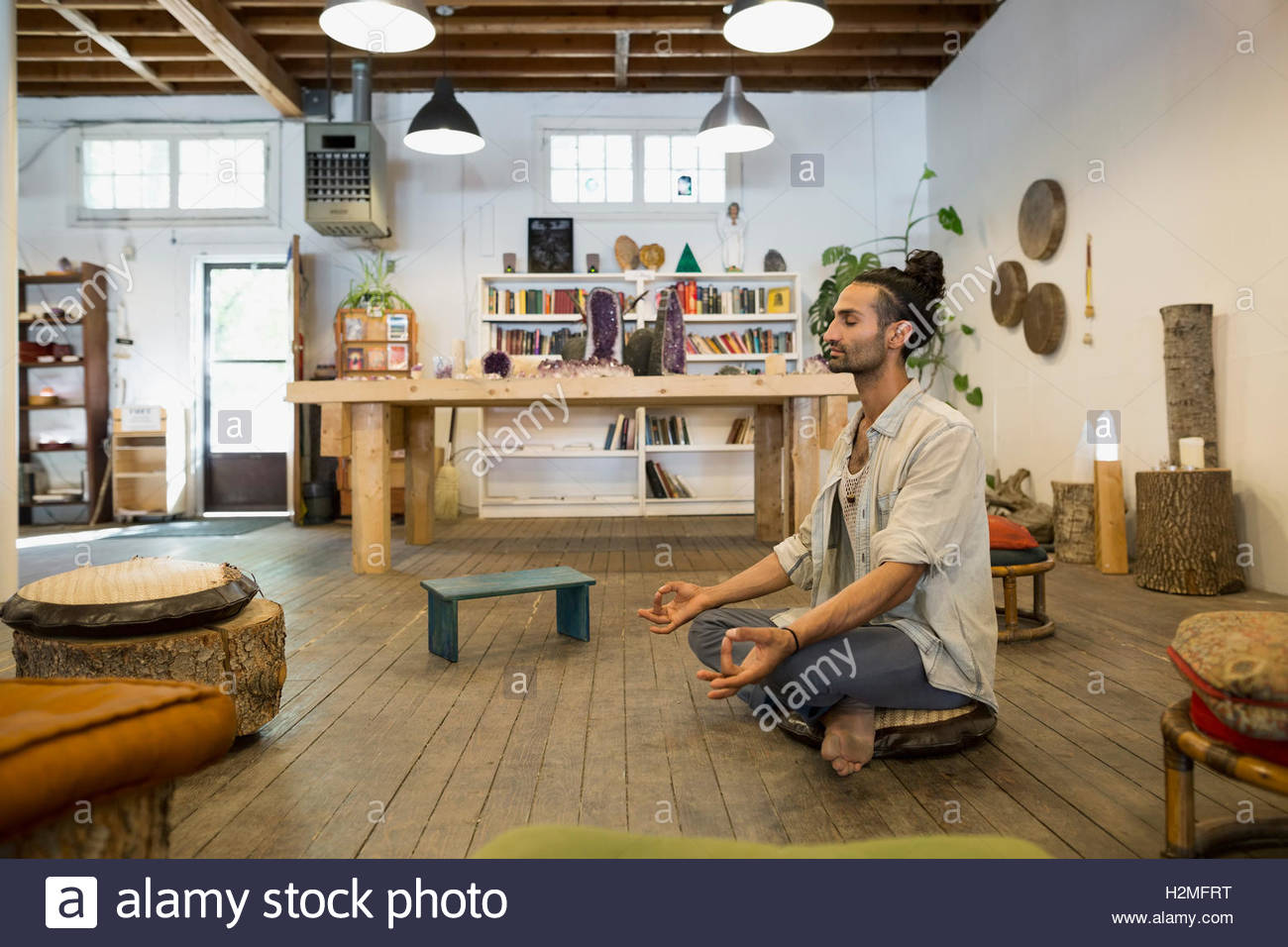 Hombre sereno meditando en la postura del loto en new age shop Foto de stock