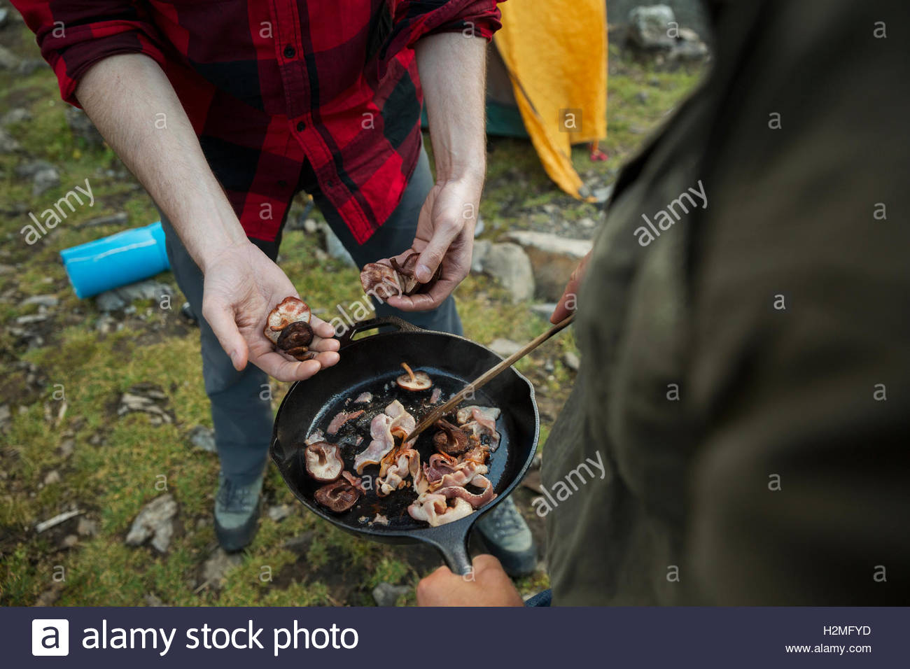 Amigos varones cocinar el tocino en la sartén en camping Foto de stock