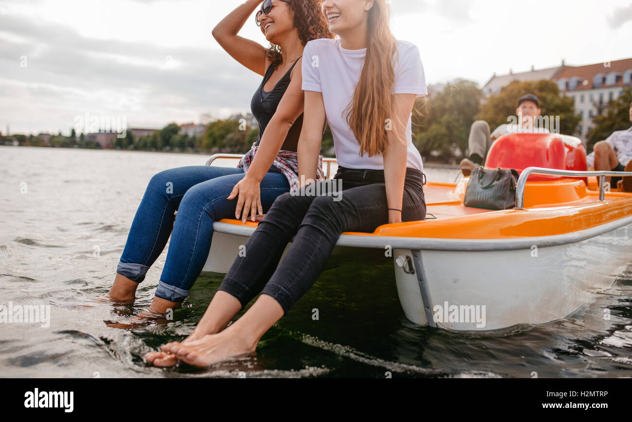 Disparó al aire libre de jóvenes amigos sentado en bote a pedal. Amigos adolescentes disfrutar de paseos en bote en el lago. Foto de stock