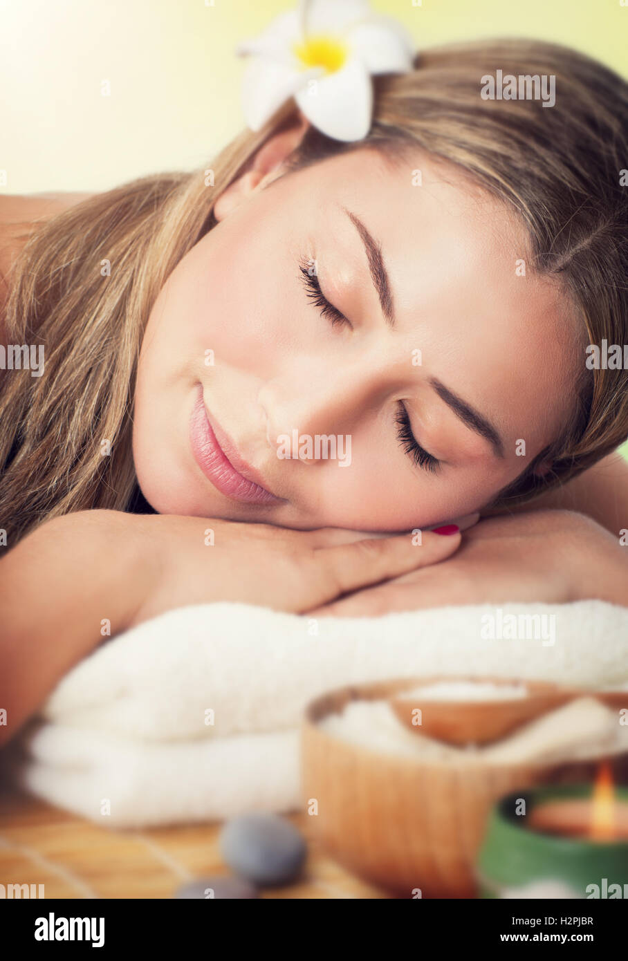 Closeup retrato de una mujer pacífica con los ojos cerrados acostada sobre una camilla de masaje en el spa de lujo, un estilo de vida saludable Foto de stock