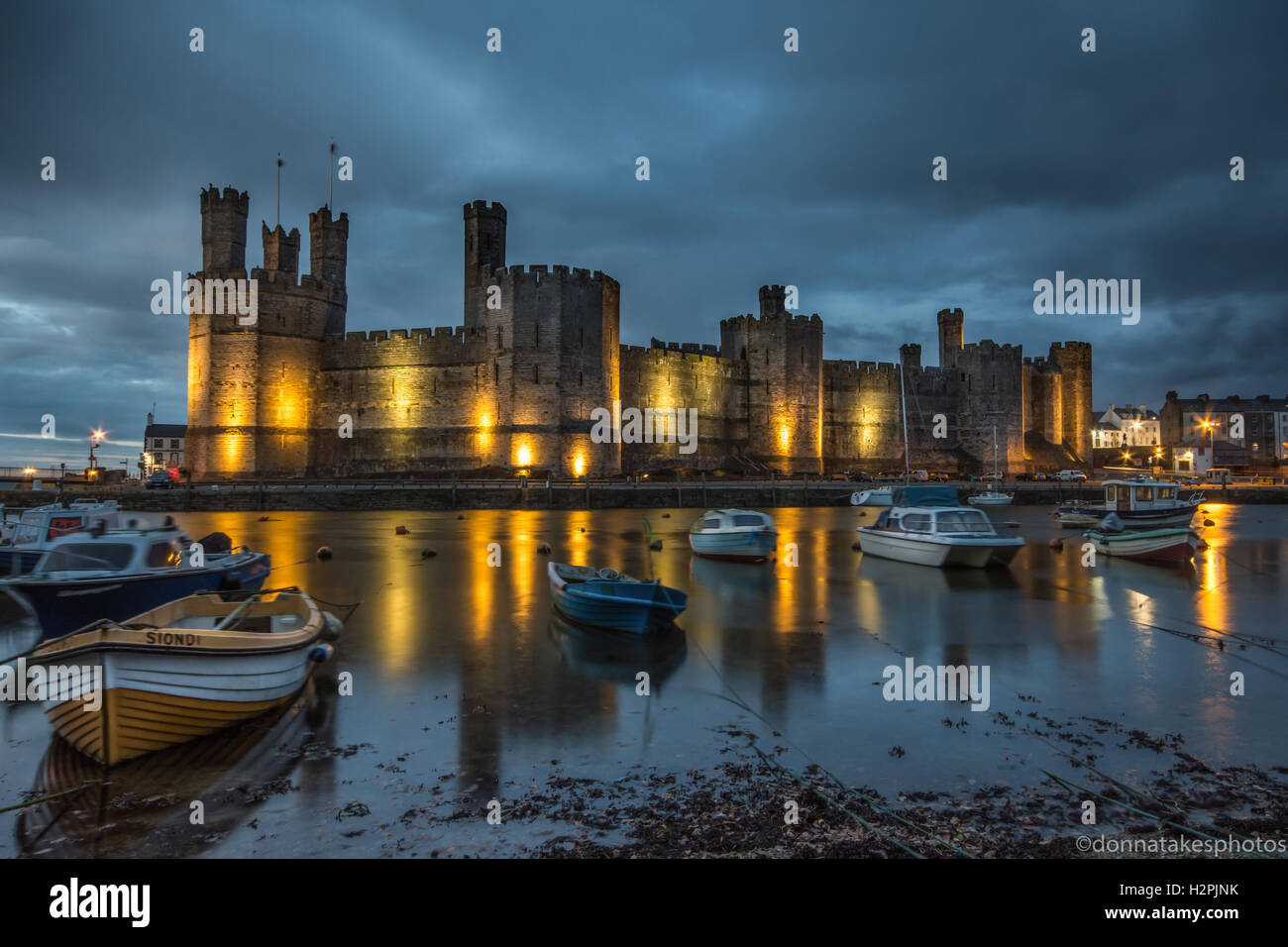 Castillo de Caernarfon iluminado en la noche, Inglaterra, Reino Unido. Foto de stock