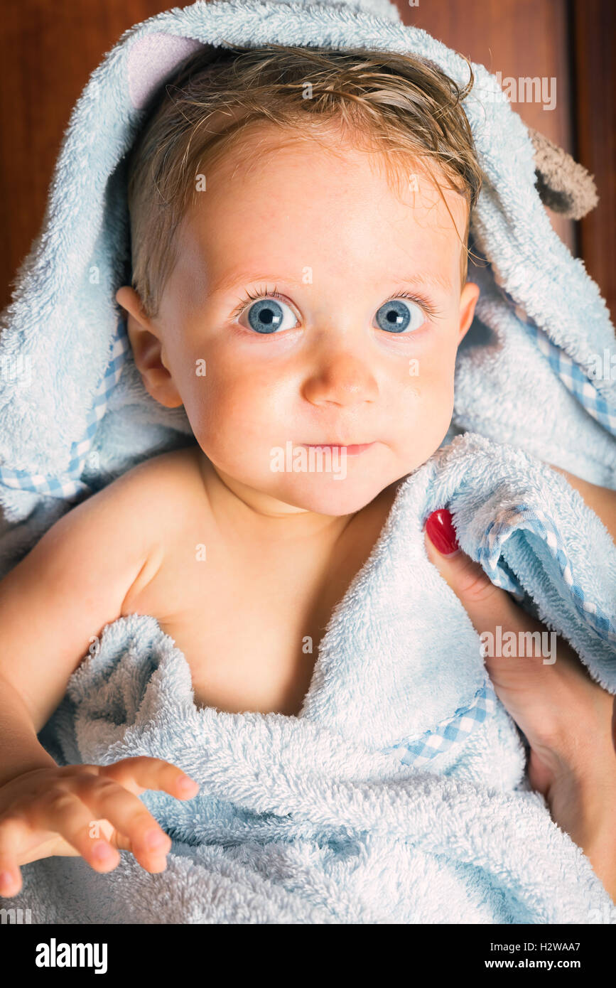 Poco bastante húmedo Baby Boy agrupados en la toalla después del baño retenidos por la madre,foto vertical. Foto de stock