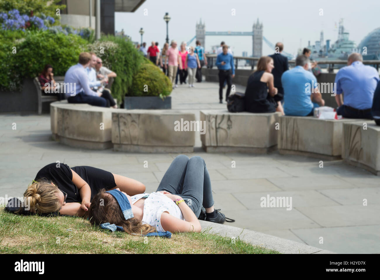 White collar worker hacen una siesta, sentarse o comer en las orillas del río Támesis, en frente del puente de la torre al mediodía,Londres,UK Foto de stock