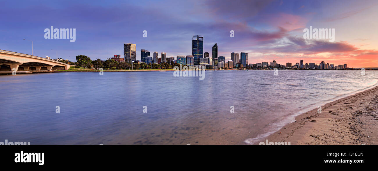 Panorama de la ciudad de Perth CBD a través del río Swan en el amanecer desde el puente a la playa arenosa con agua borrosa e iluminado business t Foto de stock