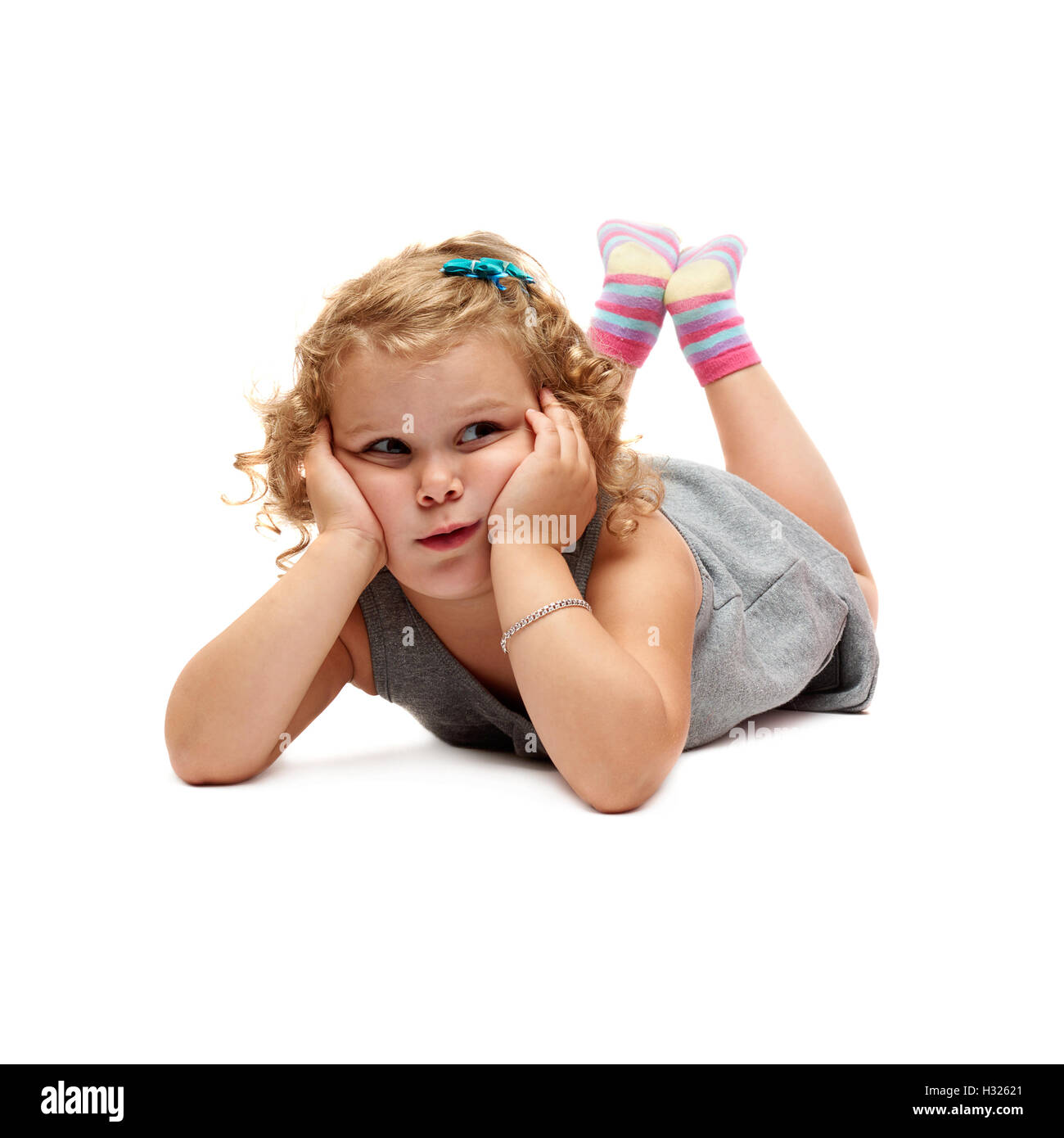 Pequeña niña recostada sobre fondo blanco aislado Foto de stock