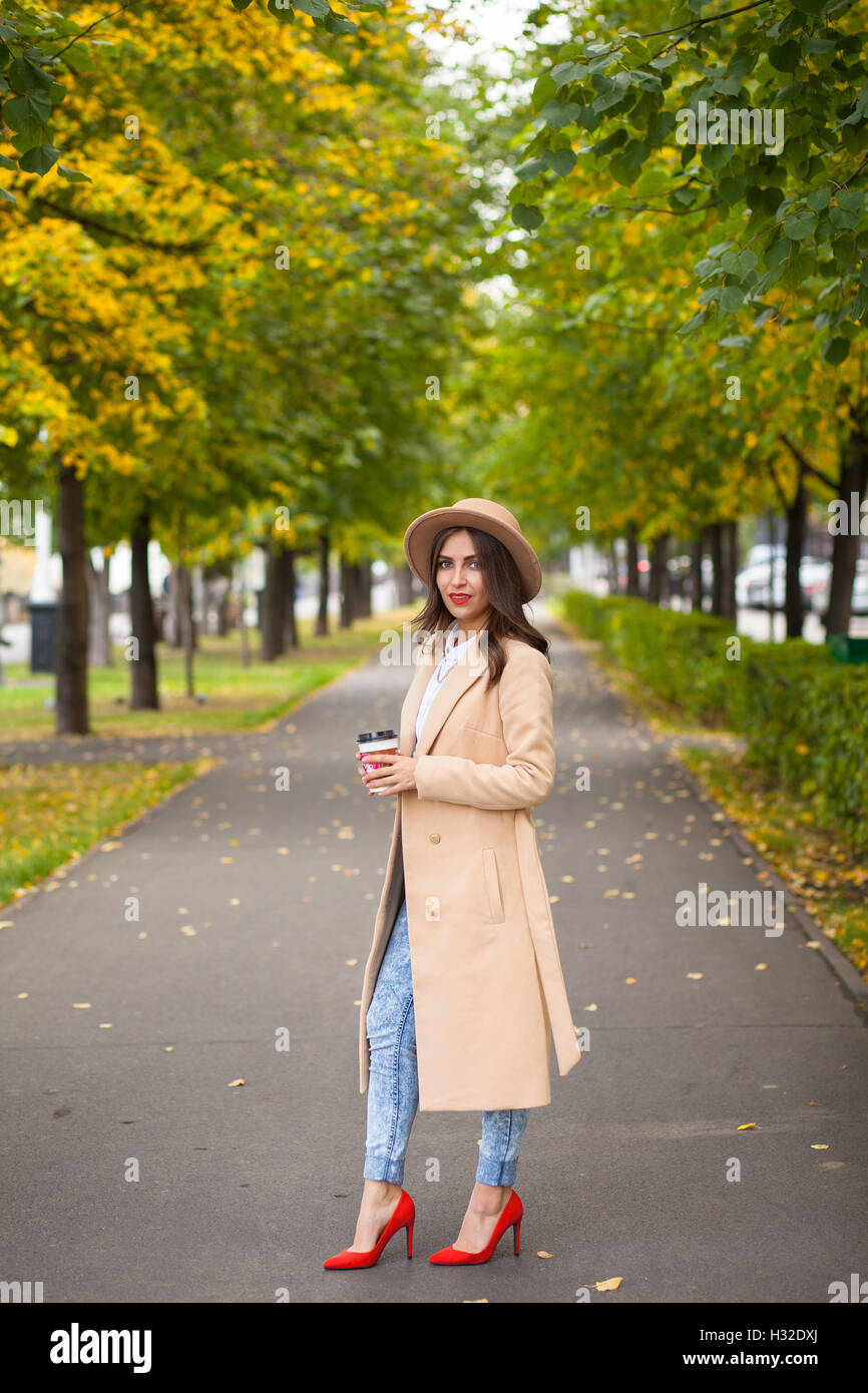 Retrato de chica con café en zapatos rojos abrigo, sombrero en el fondo de  otoño los árboles Fotografía de stock - Alamy