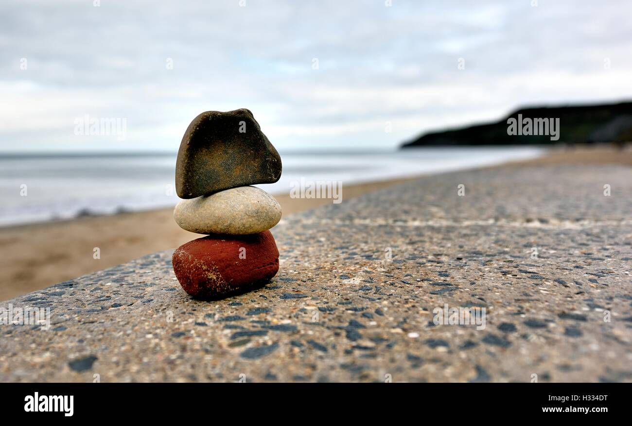 3 piedras apiladas en una pared en la costa norte de la Bahía Cayton Yorkshire, Inglaterra Foto de stock