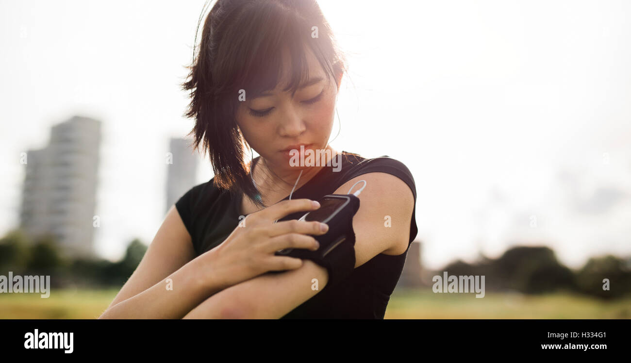 Primer plano de un bonito joven mujer china la formación al aire libre y utilizando un smartphone para supervisar su progreso. Foto de stock
