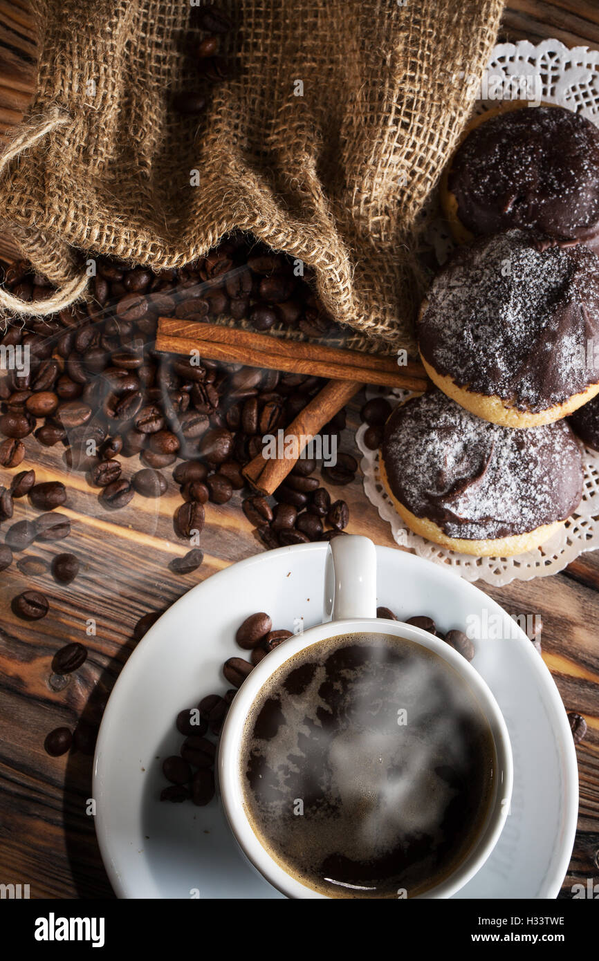 Taza de café con bollos y los granos de café sobre fondo de madera. Foto de stock
