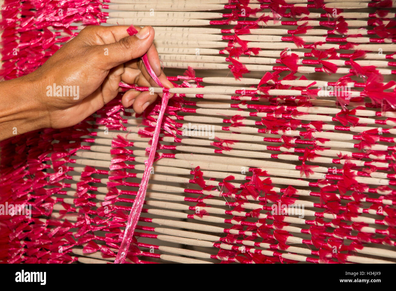 Indonesia, Bali, Singaraja, Pertenunan Berdikari taller de tejido, las manos del trabajador tinte atado resistir las roscas Foto de stock