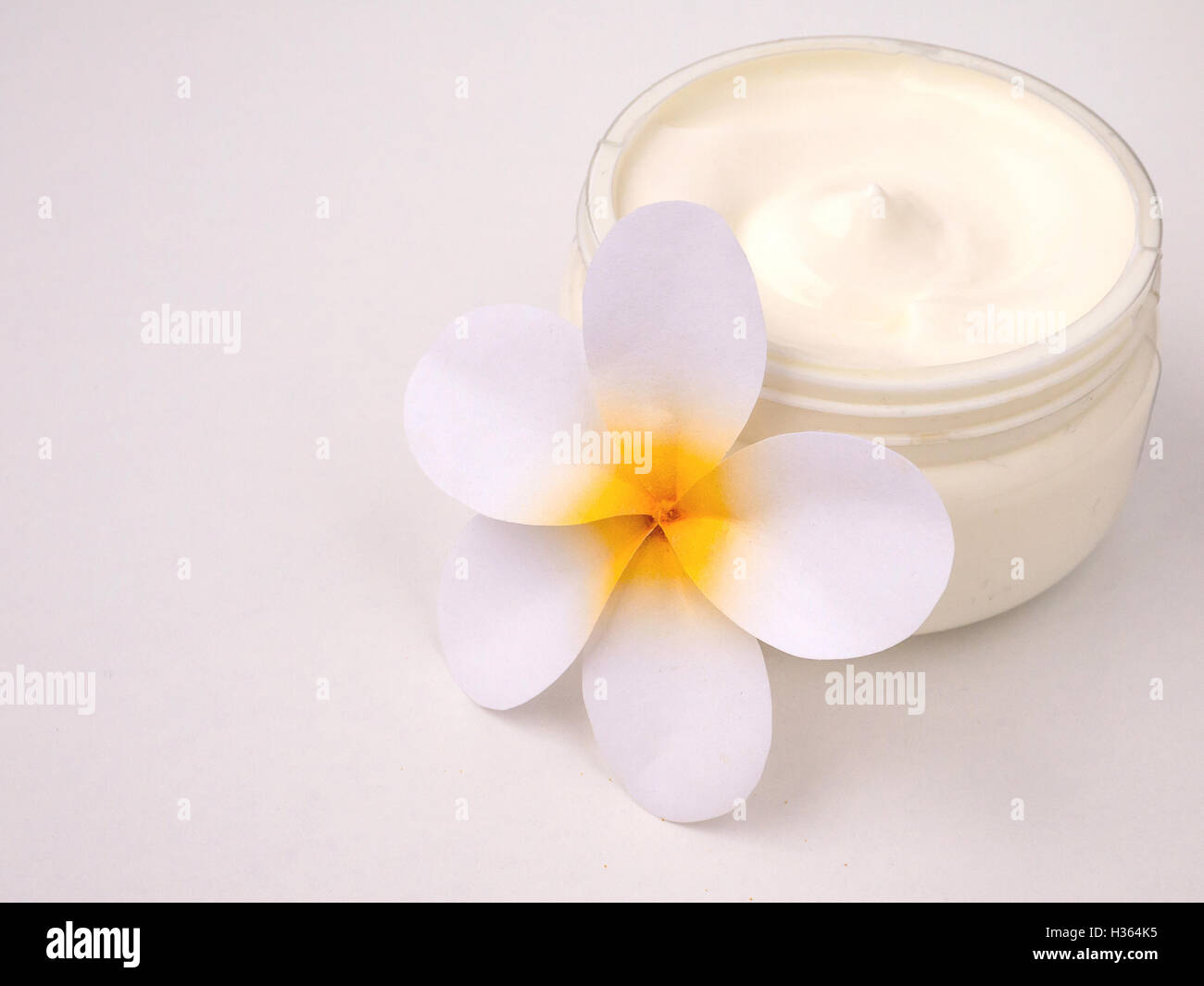 Crema blanca en la jarra y tiare flor Foto de stock