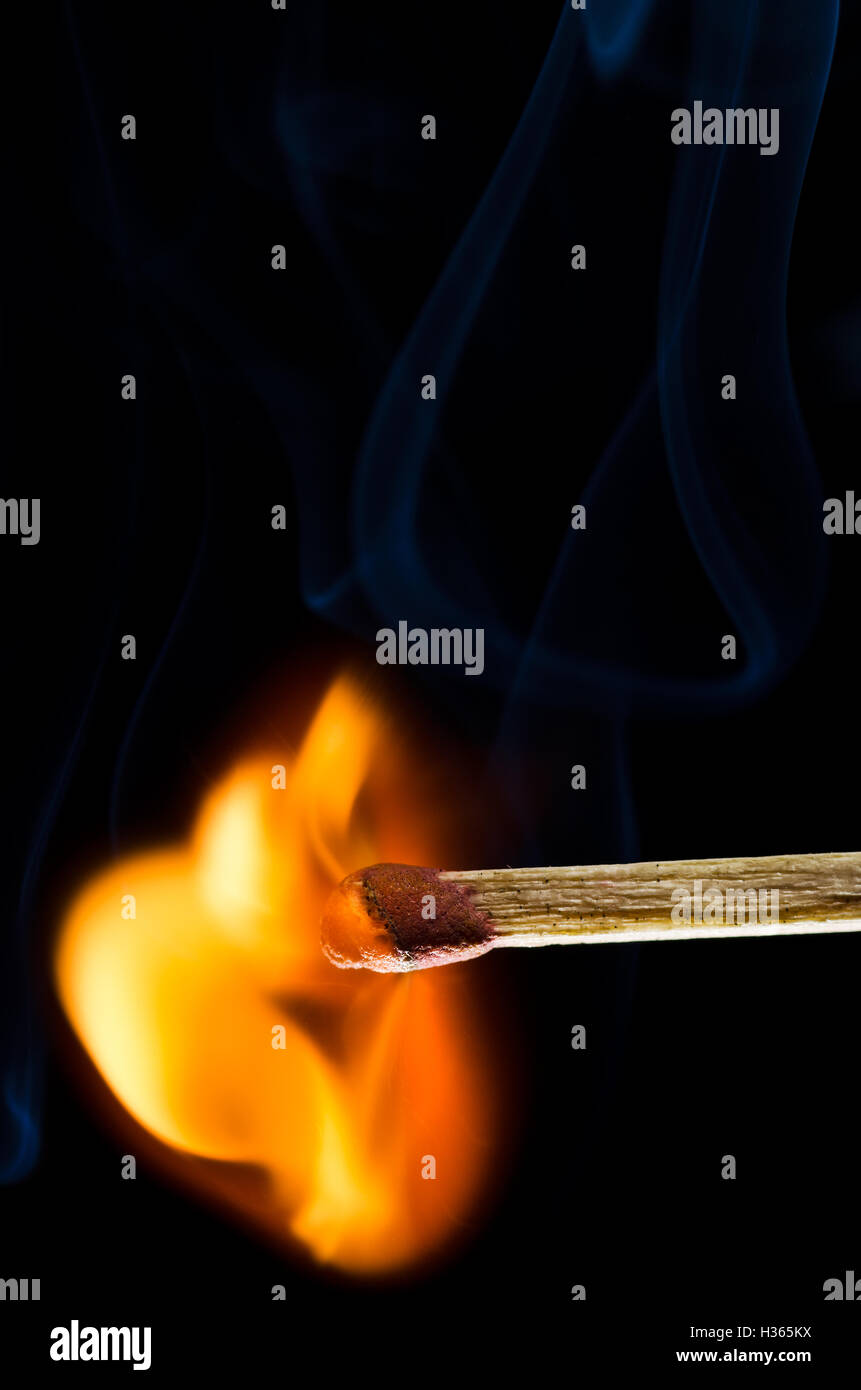 Match empezando a reventar en llamas aislado sobre fondo negro Foto de stock