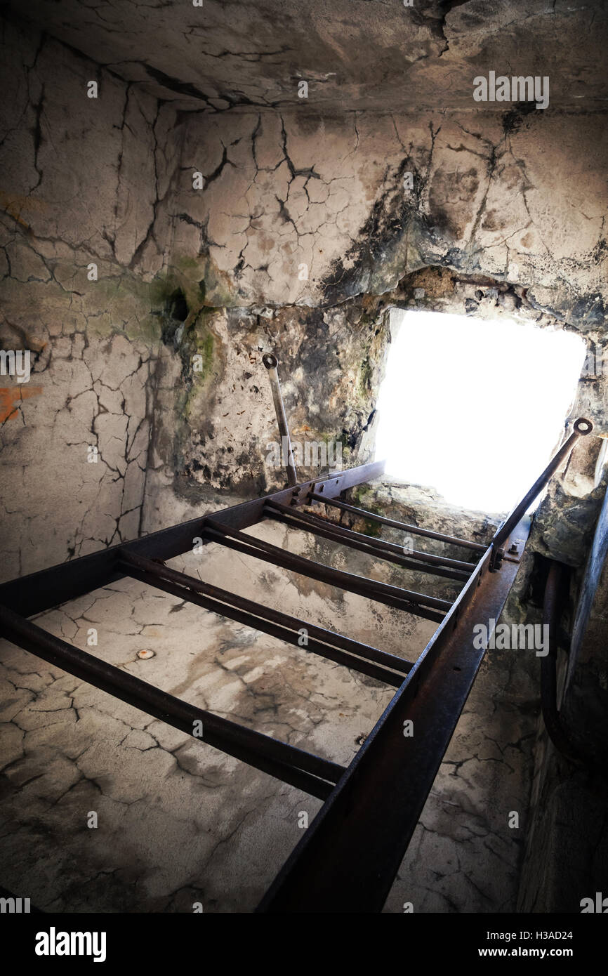 Rusted metal viejo escalera sube hasta plaza de alcantarilla brillante Foto de stock