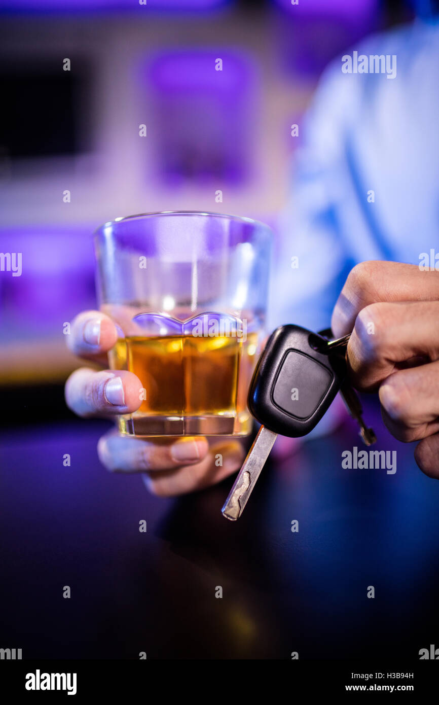 Hombre sujetando un vaso de whisky y las llaves del coche Foto de stock