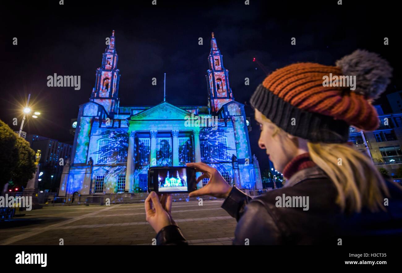 Una mujer tomar una fotografía de una instalación de arte titulado El Fénix en la piedra está proyectado a Leeds Civic Hall delante de la luz Noche de Leeds. Foto de stock