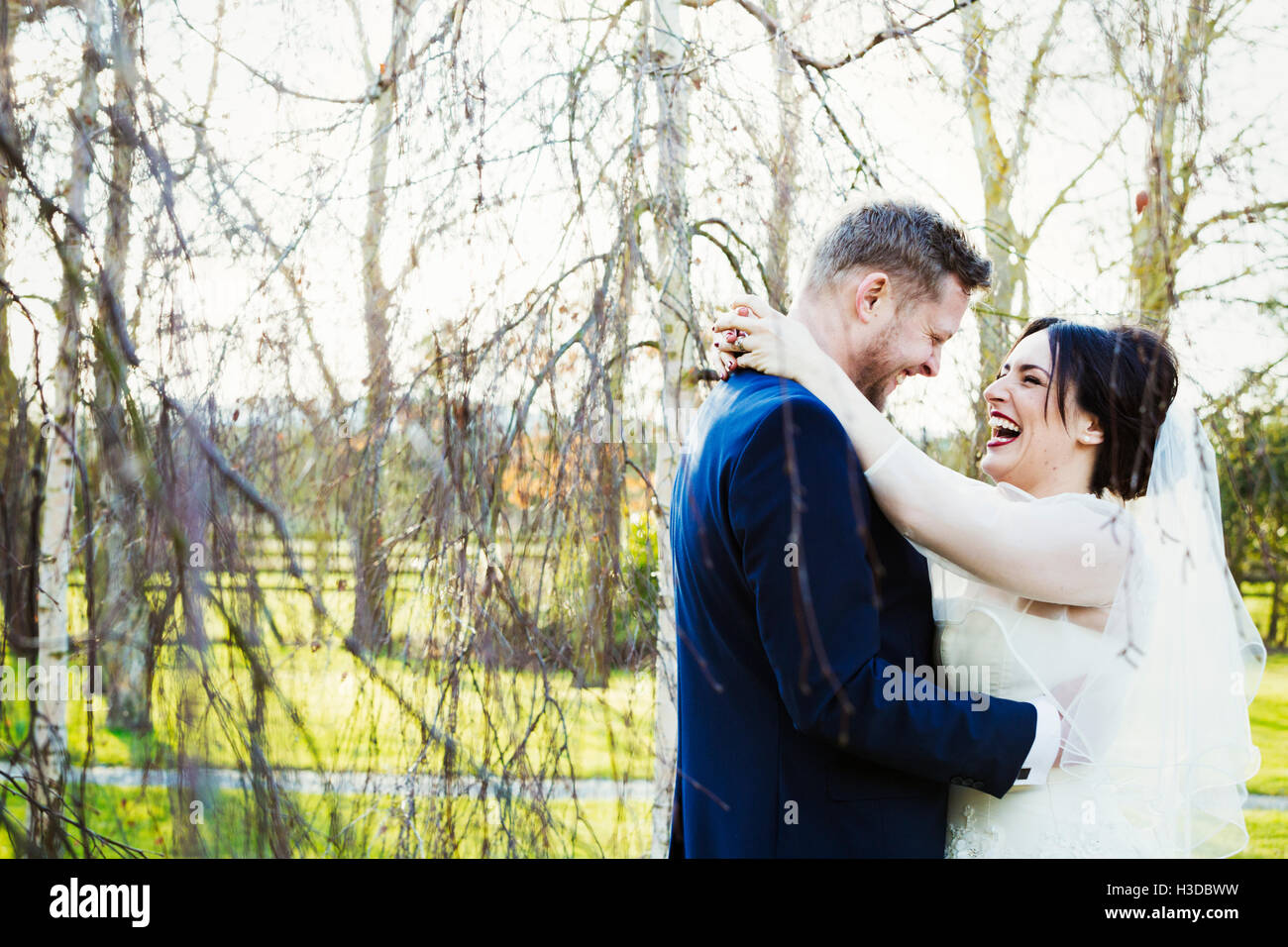 La novia y el novio en el día de su boda, riendo y abrazando. Foto de stock
