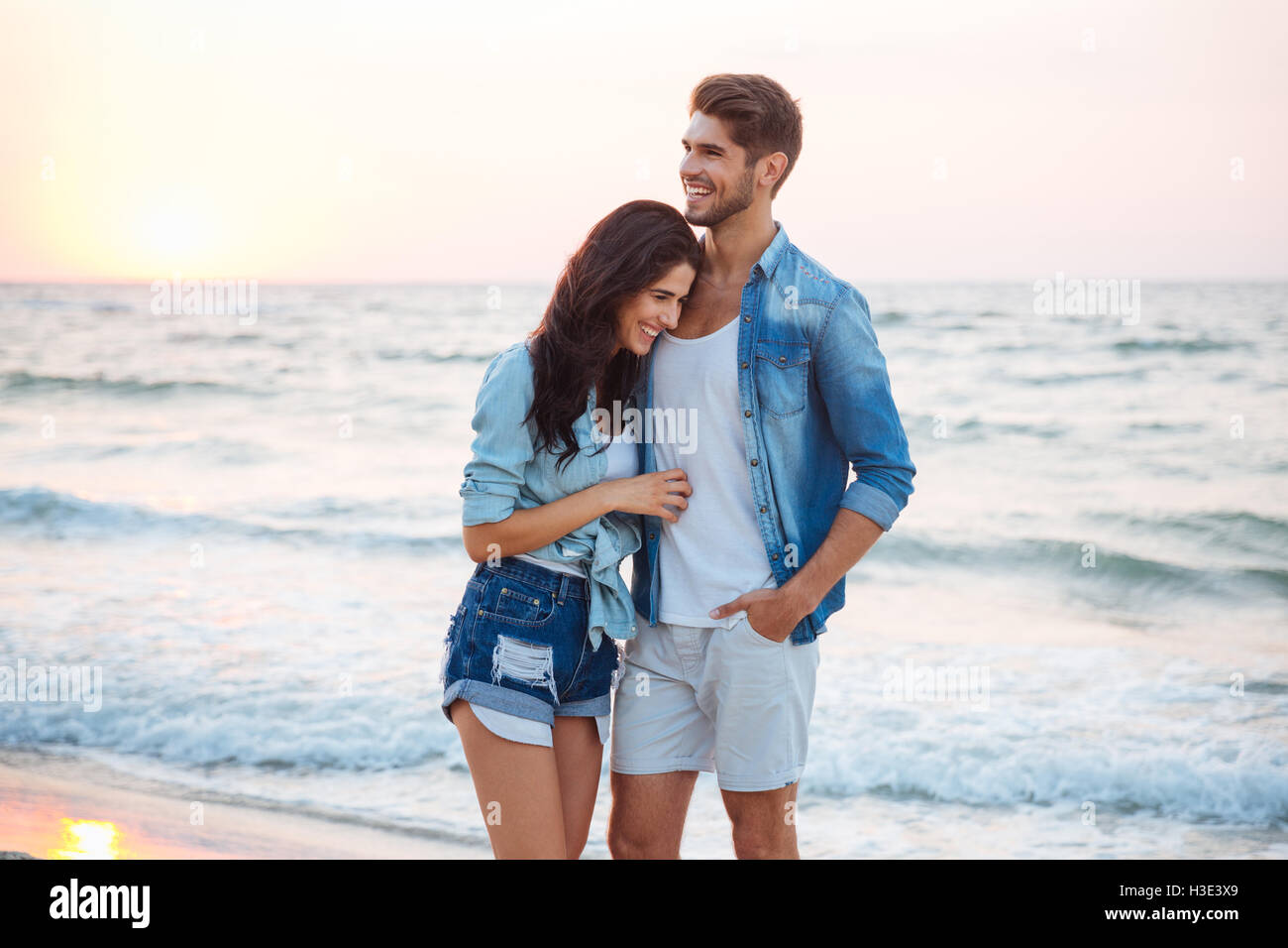 Joven pareja feliz abrazando y riendo en la playa Foto de stock