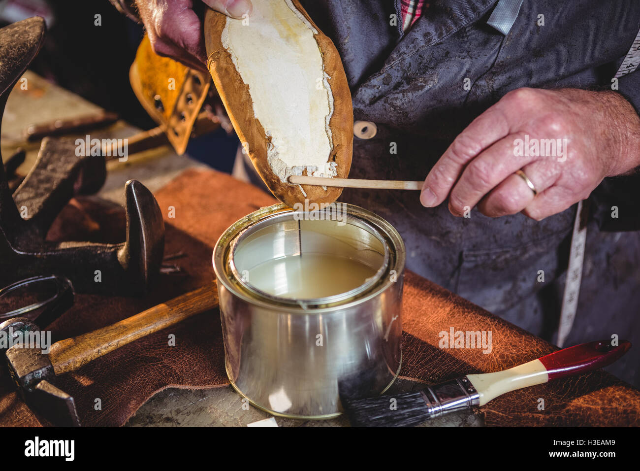 Zapatero aplicando pegamento de zapato único Fotografía de stock - Alamy