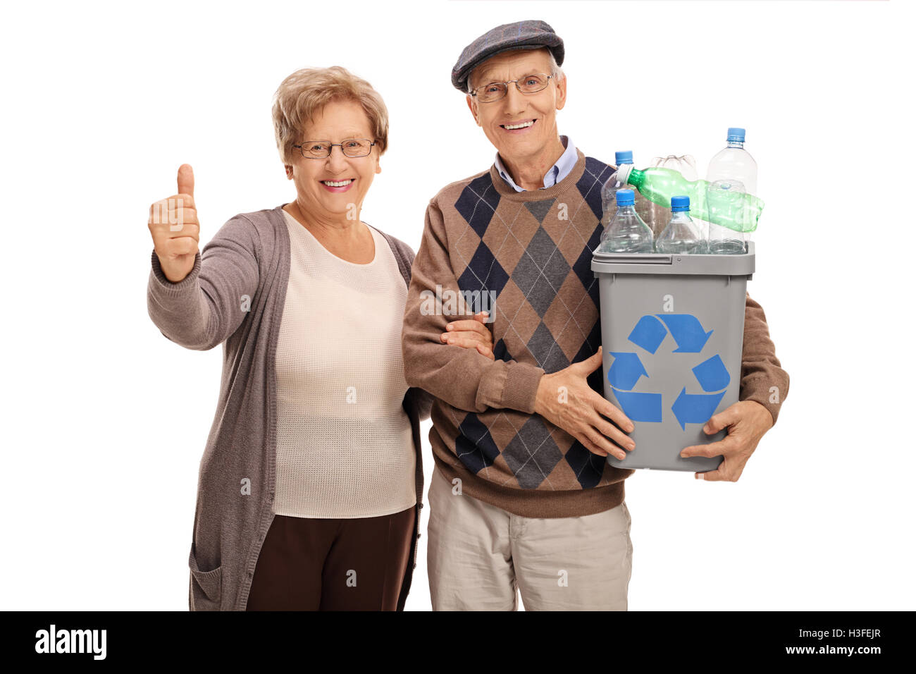 Anciano sosteniendo una bandeja llena de reciclado de botellas de plástico y una mujer madura dando un pulgar arriba aislado sobre fondo blanco. Foto de stock