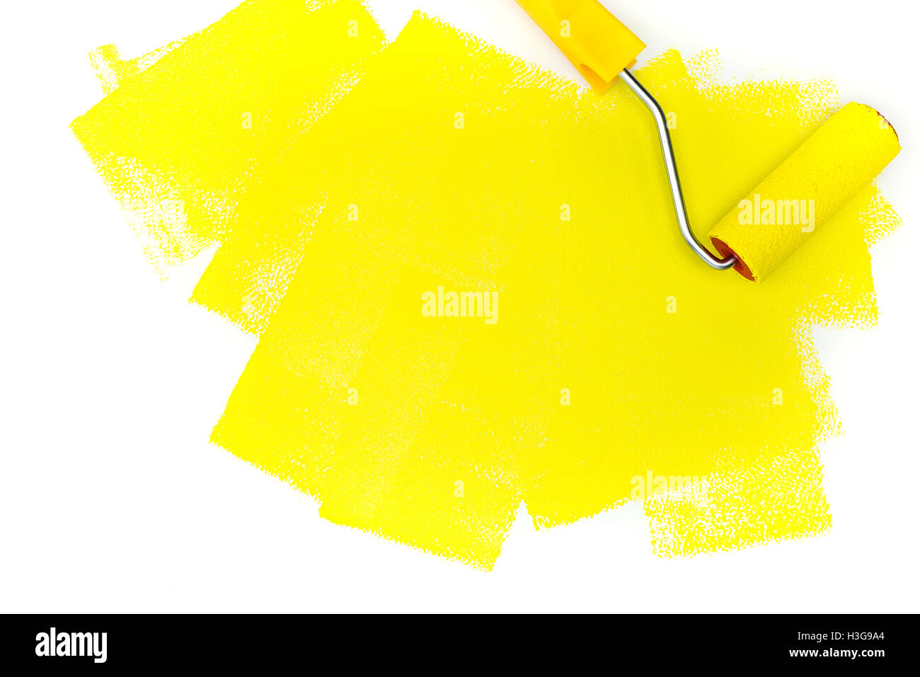 Rodillo para pintar con pintura amarilla sobre fondo blanco. Foto de stock