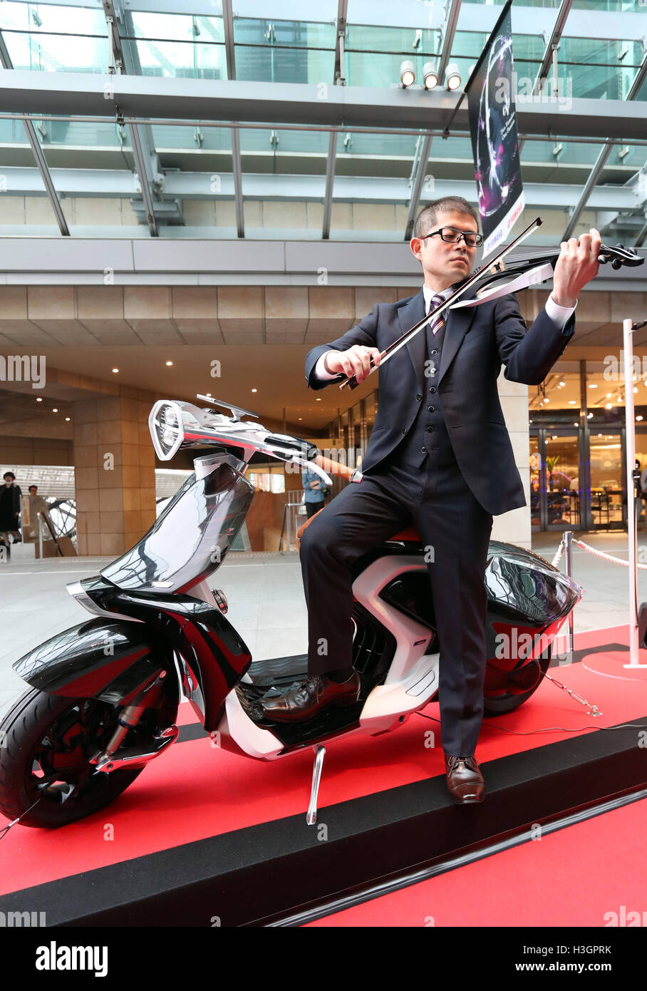 Tokio, Japón - El gigante japonés de instrumentos musicales Yamaha  Corporation empleado desempeña violín eléctrico junto al concepto "scooter  04Gen' en Tokio, el sábado, 8 de octubre de 2016. Instrumento musical  gigante