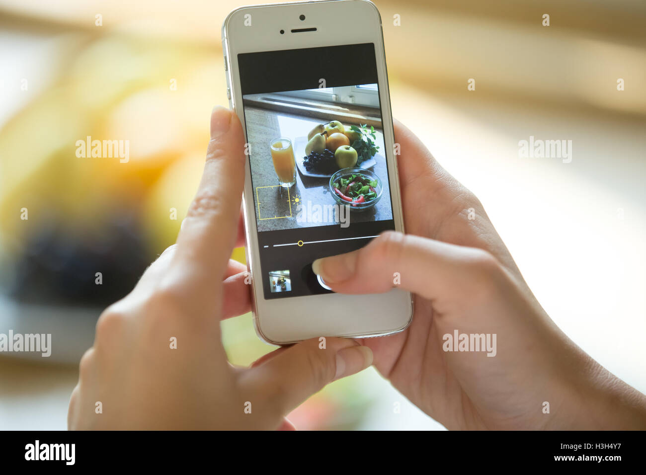 Manos sosteniendo un teléfono con alimentos imagen en la pantalla Foto de stock