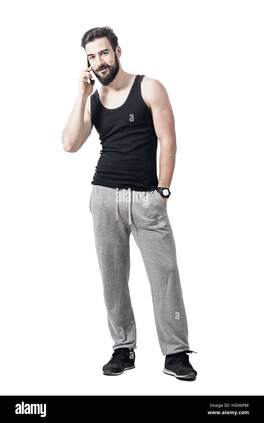 Colocar joven hombre barbado en ropa deportiva sonreír y hablar por el  teléfono celular. Longitud de cuerpo completo retrato aislado en blanco  Fotografía de stock - Alamy