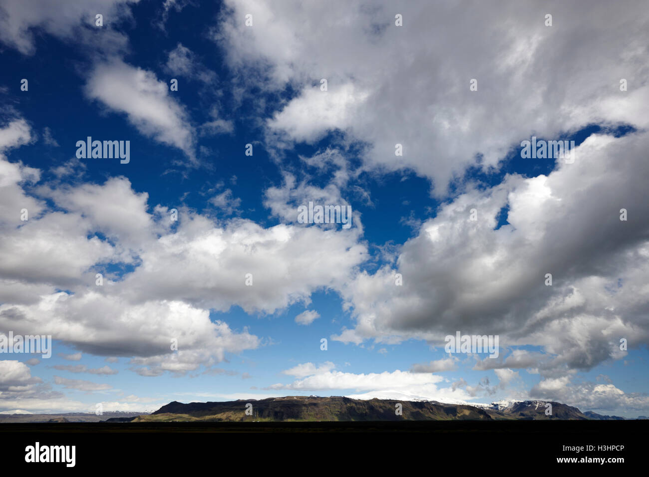 Las nubes blancas en el cielo azul sobre abrir tierras agrícolas en el sur de Islandia Foto de stock