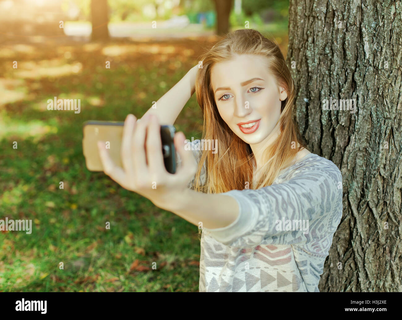 Hermosa chica con ojos azules hace selfie afuera Foto de stock